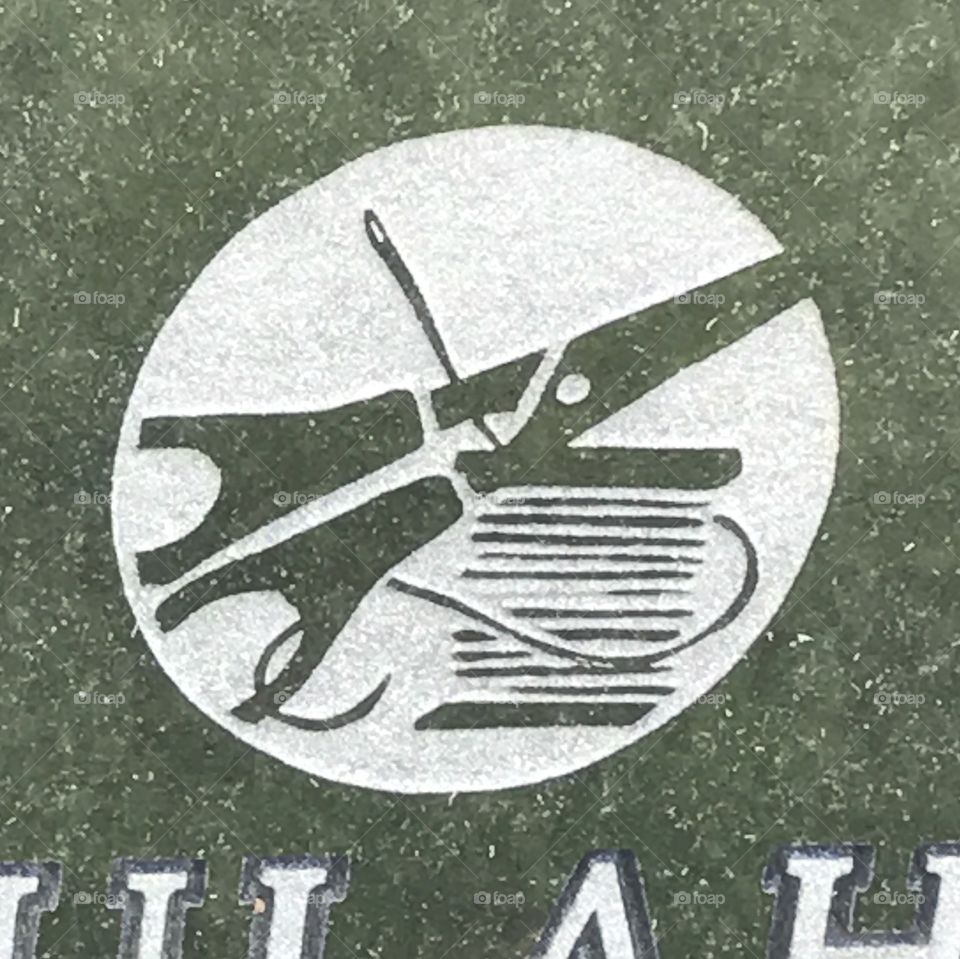 A picture engraved on a headstone of scissors, a needle and thread