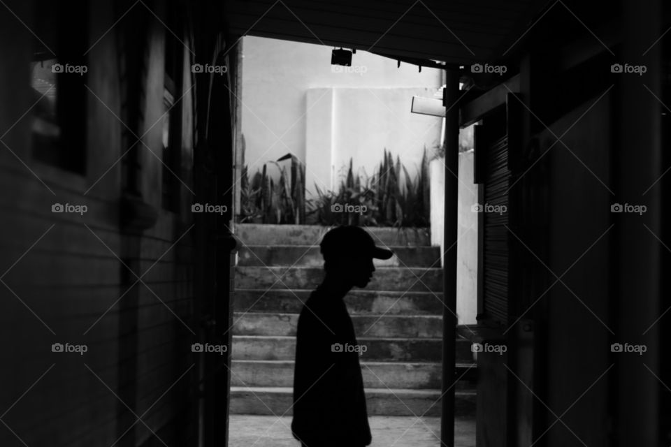 Silhouette of a man standing at a corner of a random alley.