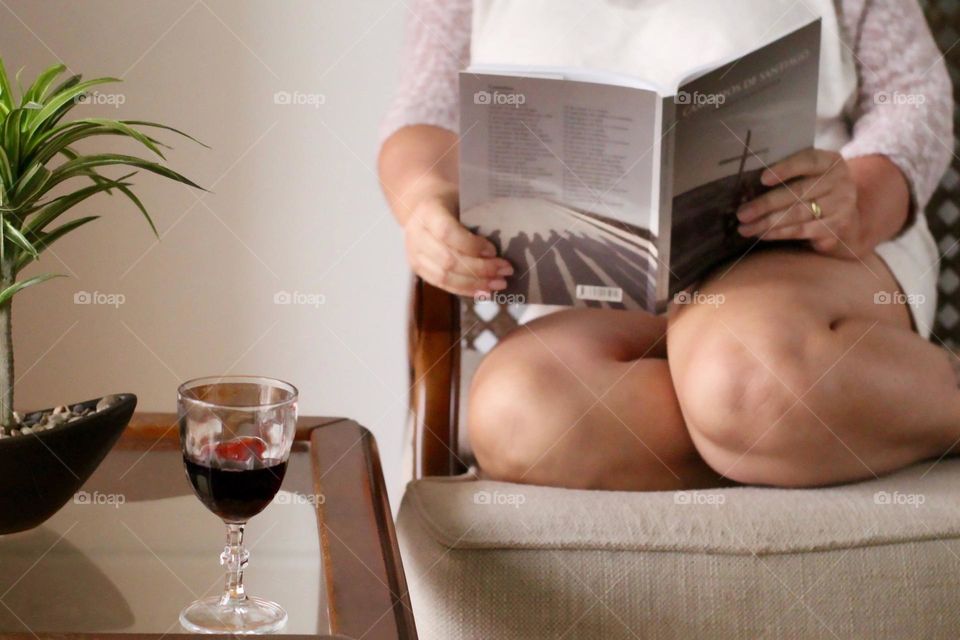 Woman reading a book with a glass of red wine