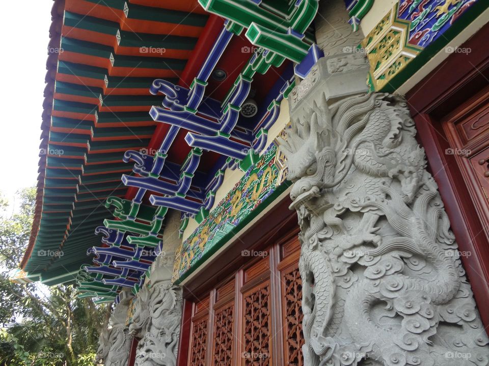 Details of an oriental temple with a roof full of colors and columns with sculptures 