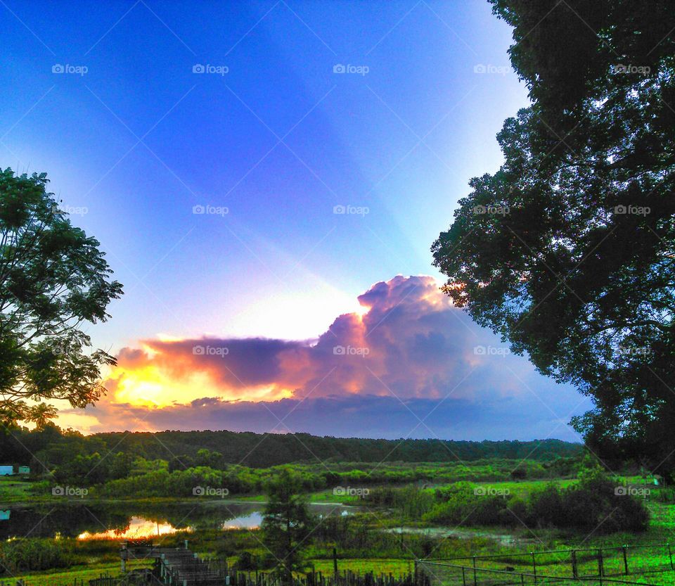 Stormy skies and sunrise. Colorful skies, storms and sunbeams at sunrise over lake