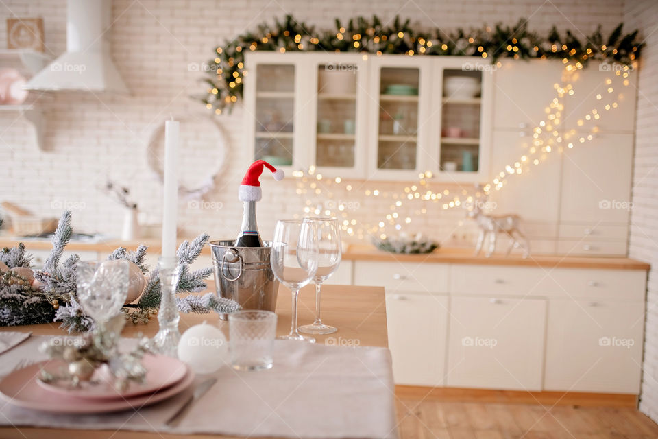 Festive winter cozy kitchen interior with garlands, decorations and gifts.  Christmas dinner at the decorated table.