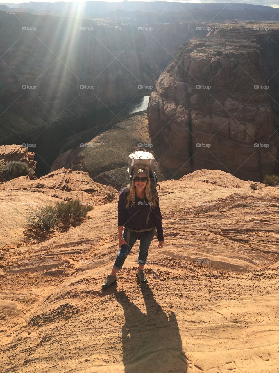 Female hiker at horseshoe bend in page, Arizona, carrying a toddler in backpack.