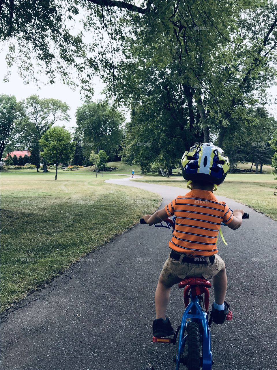 Young boy riding a bicycle down a park path