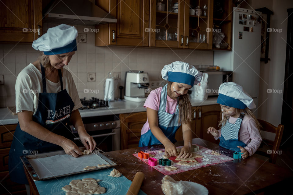 Little sisters with grandma cooking the biscuits 