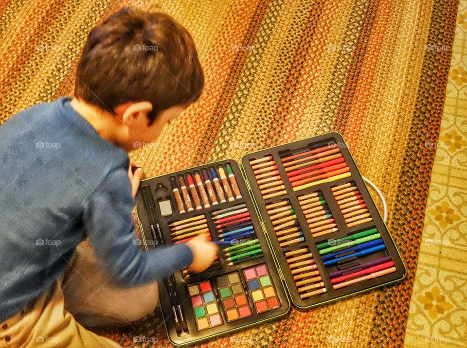 Young Artist With Art Supplies. Boy Opening A Kit Of Crayons And Colored Pencils
