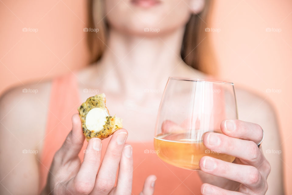 Woman holding a bitten tart and a glass of wine 