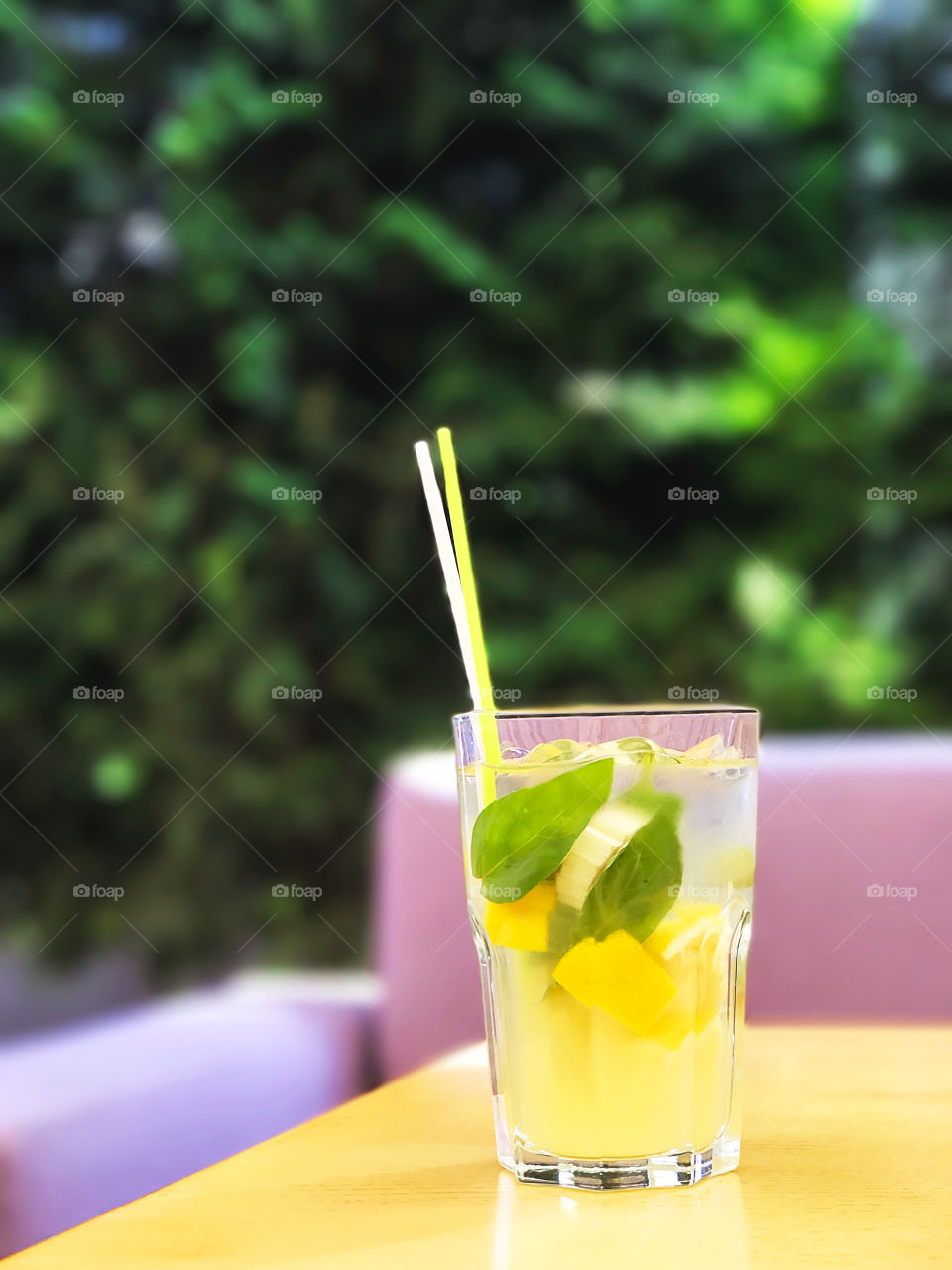 Cold refreshing citrus lemonade with straws on colorful lilac and yellow background 