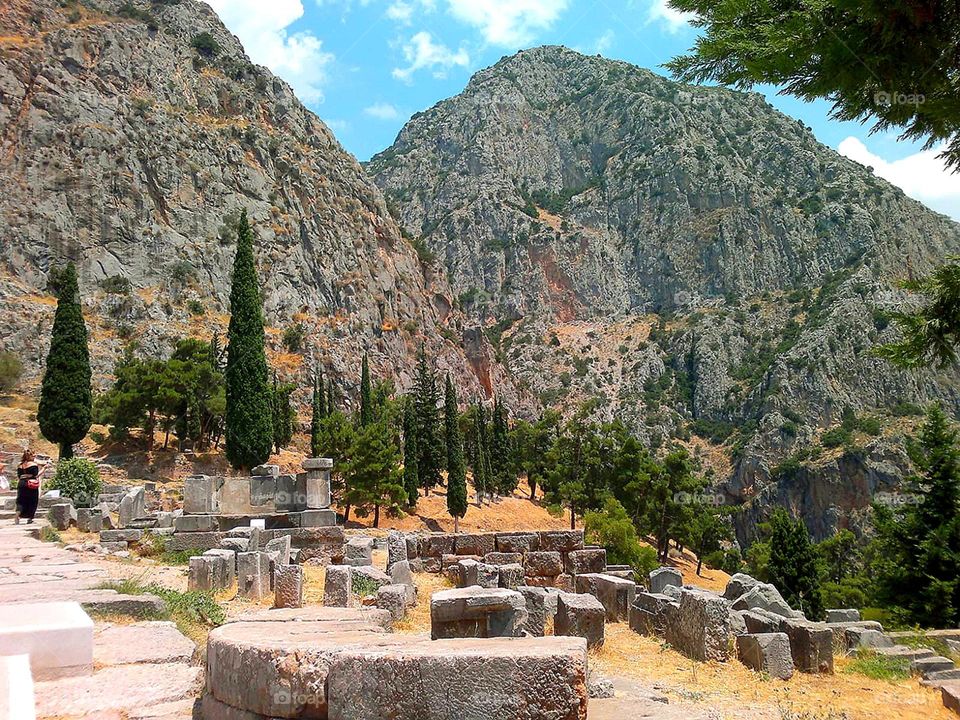 City or village. Open spaces. Greece. Delphi. Among the rare green trees lie the ruins of the ancient temple of Apollo. Mount Parnassus rises in the background.