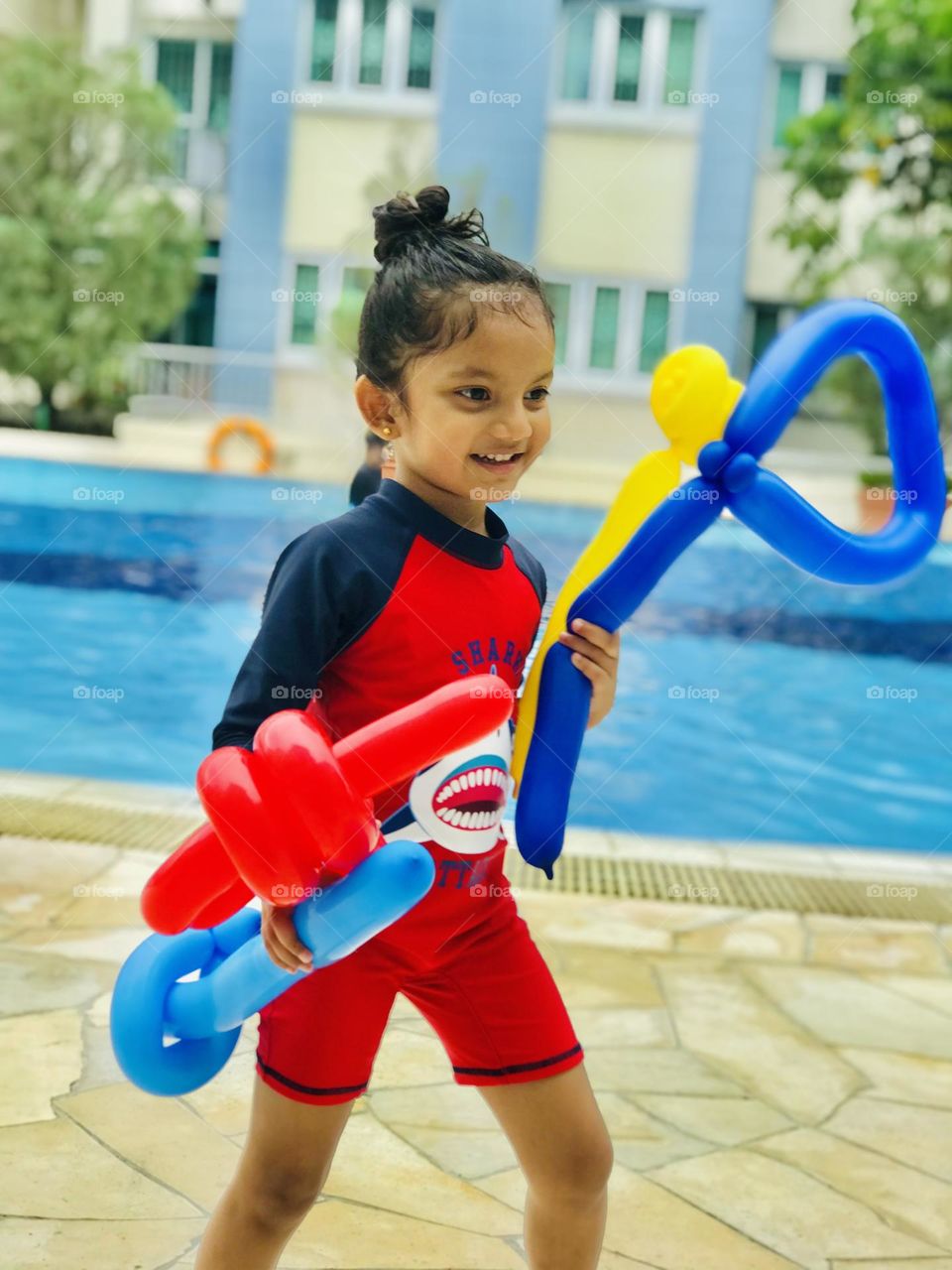 Girl enjoying at swimming pool with balloons and smiles.