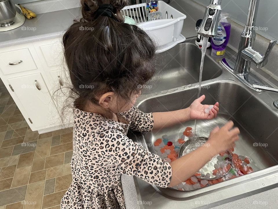 Toddler girl washes rocks in sink, toddler cleans fish tank rocks, toddler helps mommy, Mommy’s little helper 