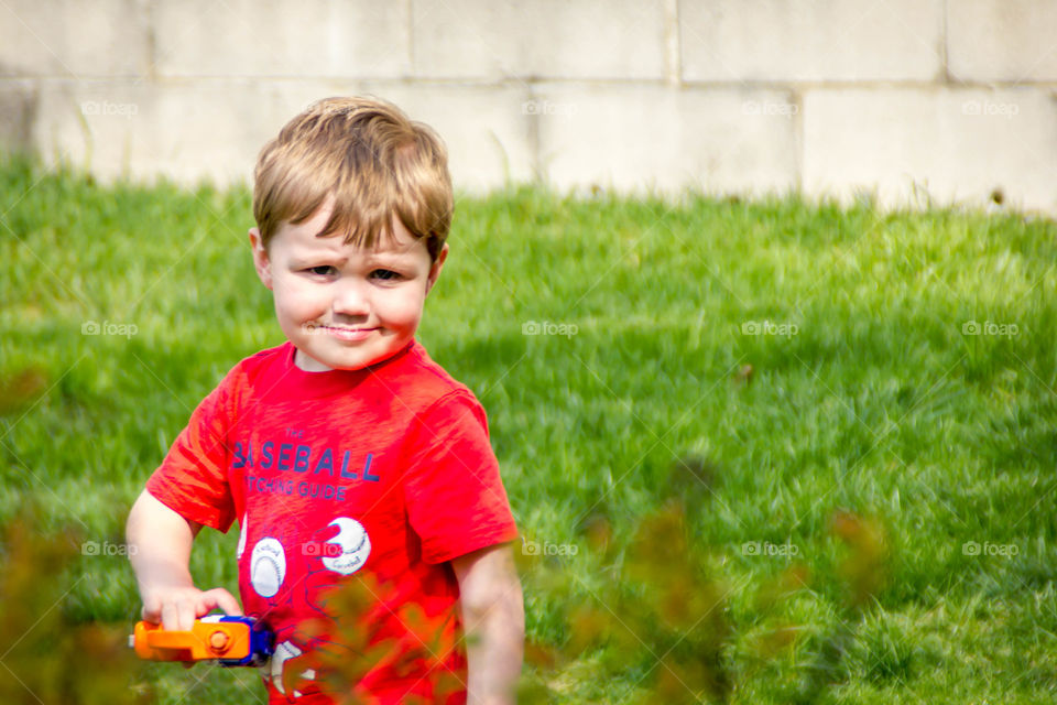 Little boy on grassy landscape holding toy in hand