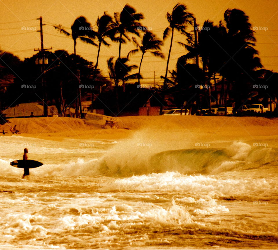 Surfer waiting to enter water in larger surf Waianae Hawaii. 