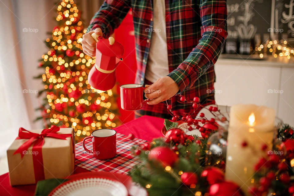 Festive winter cozy kitchen interior with garlands, decorations and gifts.  Christmas dinner at the decorated table.