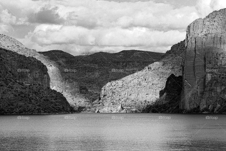 Dramatic lighting on a cloudy day creates long shadows on the rock walls at Canyon Lake in Arizona