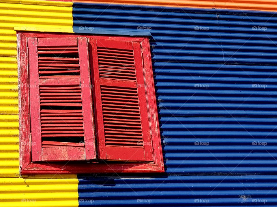 red window on a colourful yellow blue and orange wall in La Boca, Buenos Aires Argentina