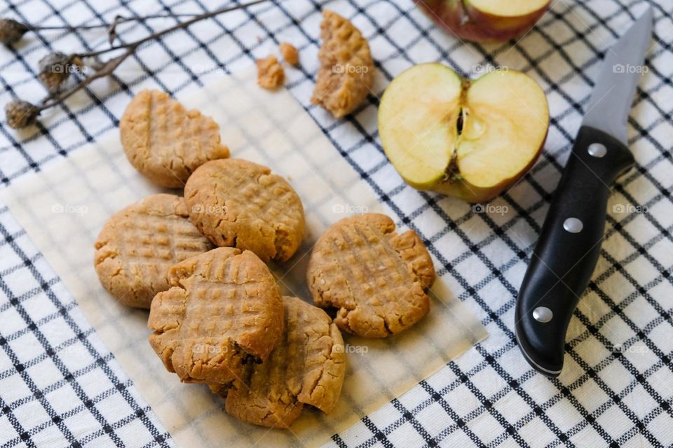 American peanut butter cookies, cut apple, dried flowers and khife on the checkered napkin