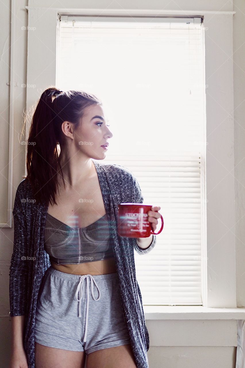 Brunette girl in her pajamas drinking a cup of tea before school in the morning. 