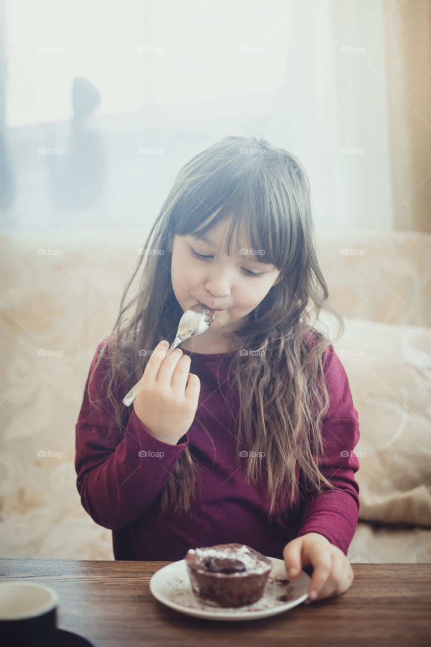 Little girl eating the chocolate muffin