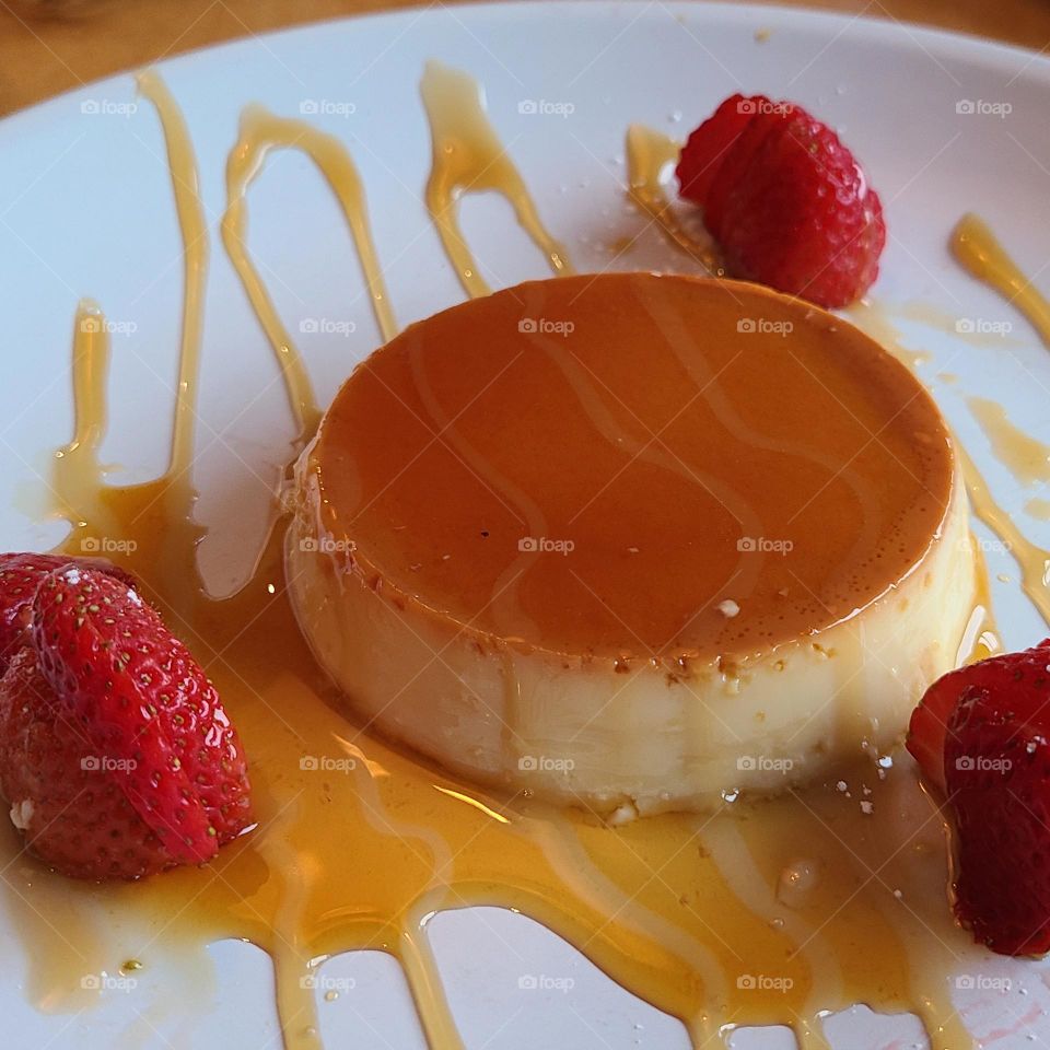 Beautiful plate of flan with caramel sauce on a white plate with delicious strawberries 