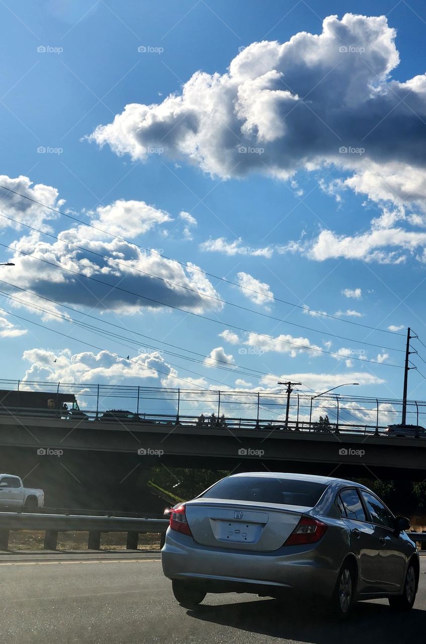 view of a car approaching a bridge overpass with other cars driving above during commuter traffic on a week day afternoon in Oregon