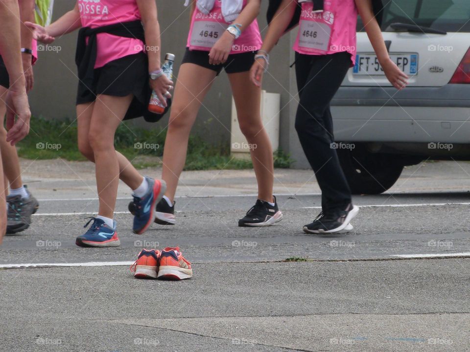 A pair of sneakers abandoned on a road seems to be watching the participants of a charity march