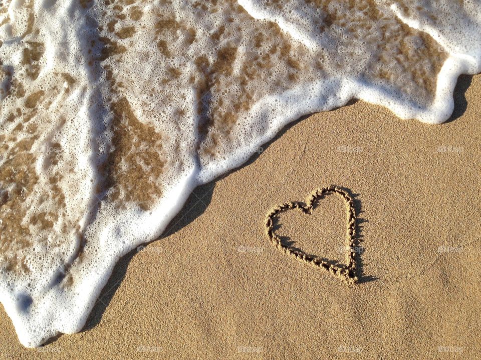Heart drawn in the sand beach near the ocean surf