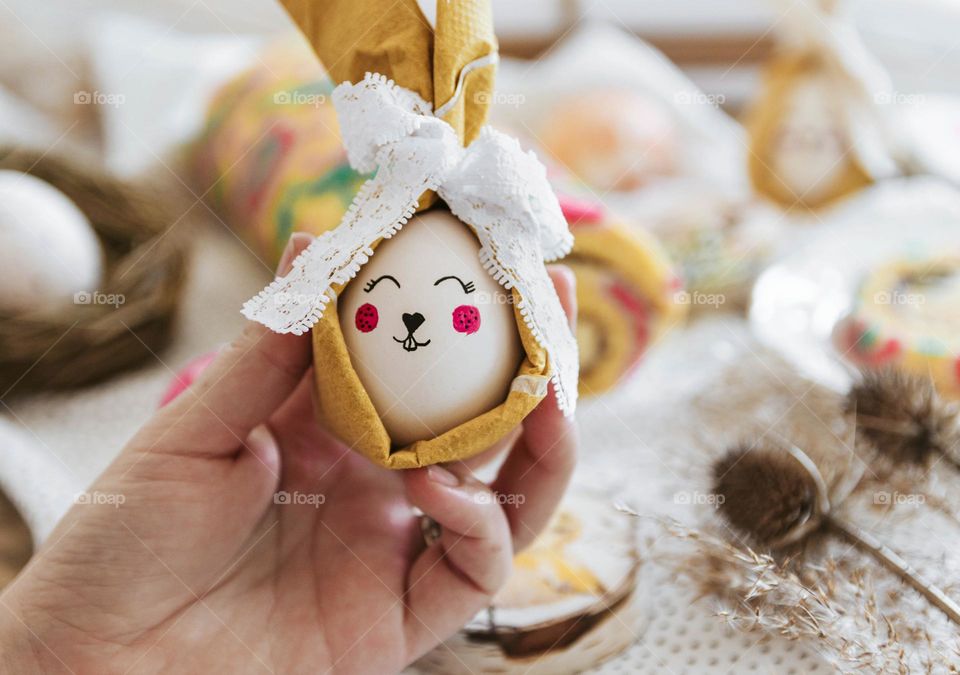 Close-up of hand holding painted easter egg decorated as a bunny