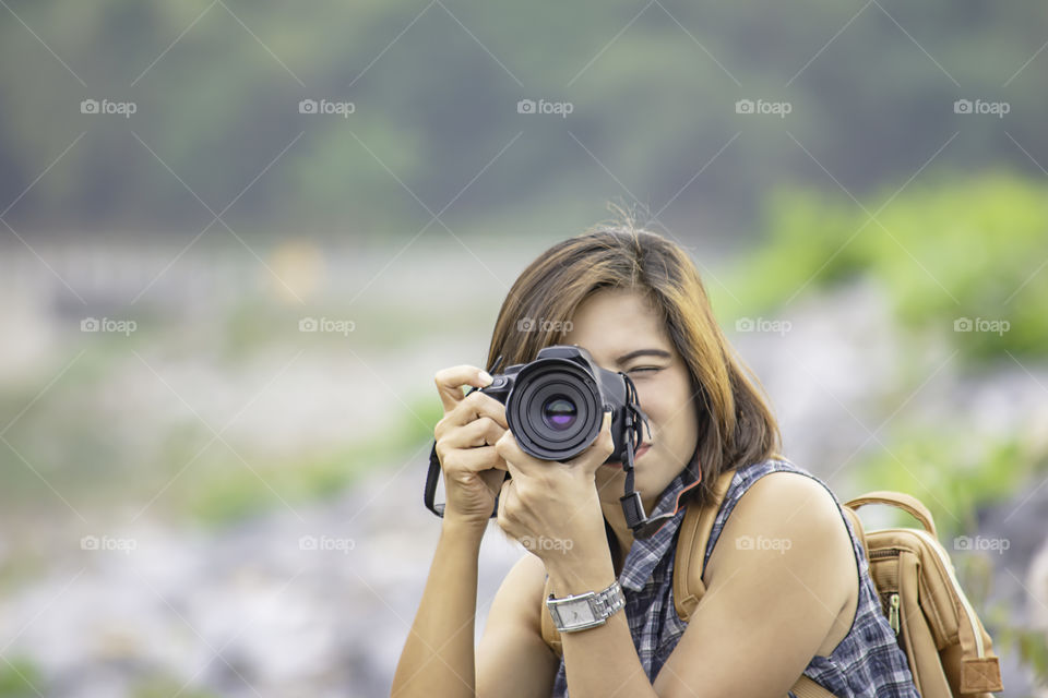 Hand woman holding the camera Taking pictures background Wang Bon dam Nakhon nayok , Thailand.