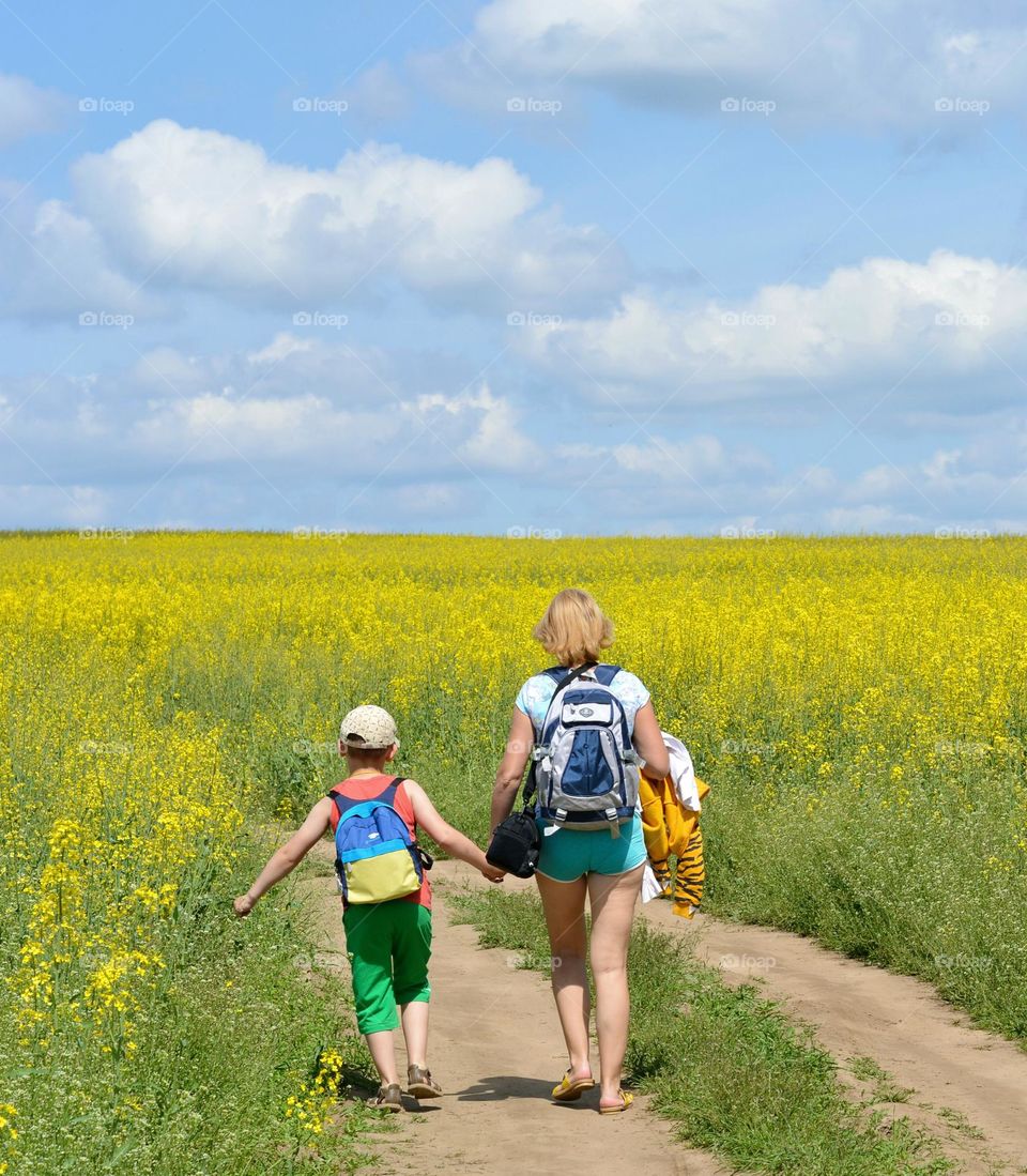 family mother and son walking outdoor rapeseed field background spring and summer time