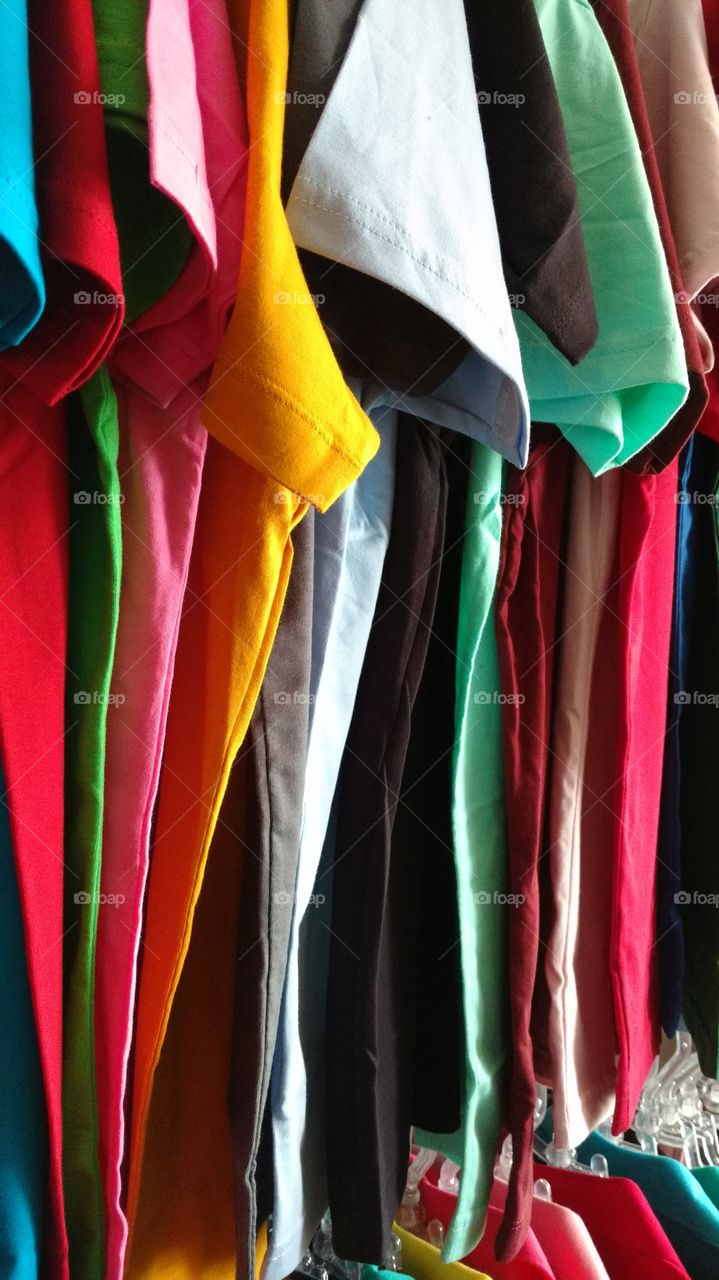 Camisetas. Roupas coloridas em cabides de loja.