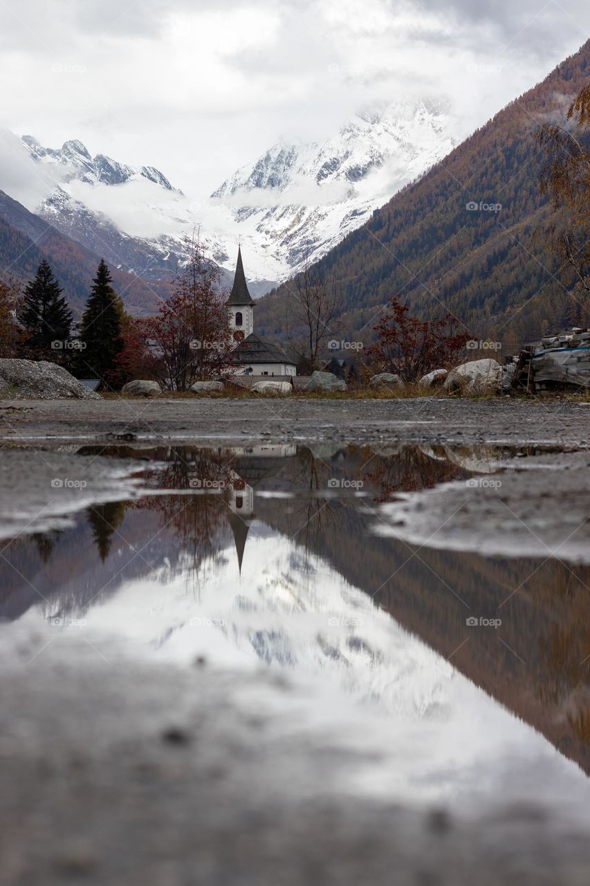 Reflection of church in water puddle.