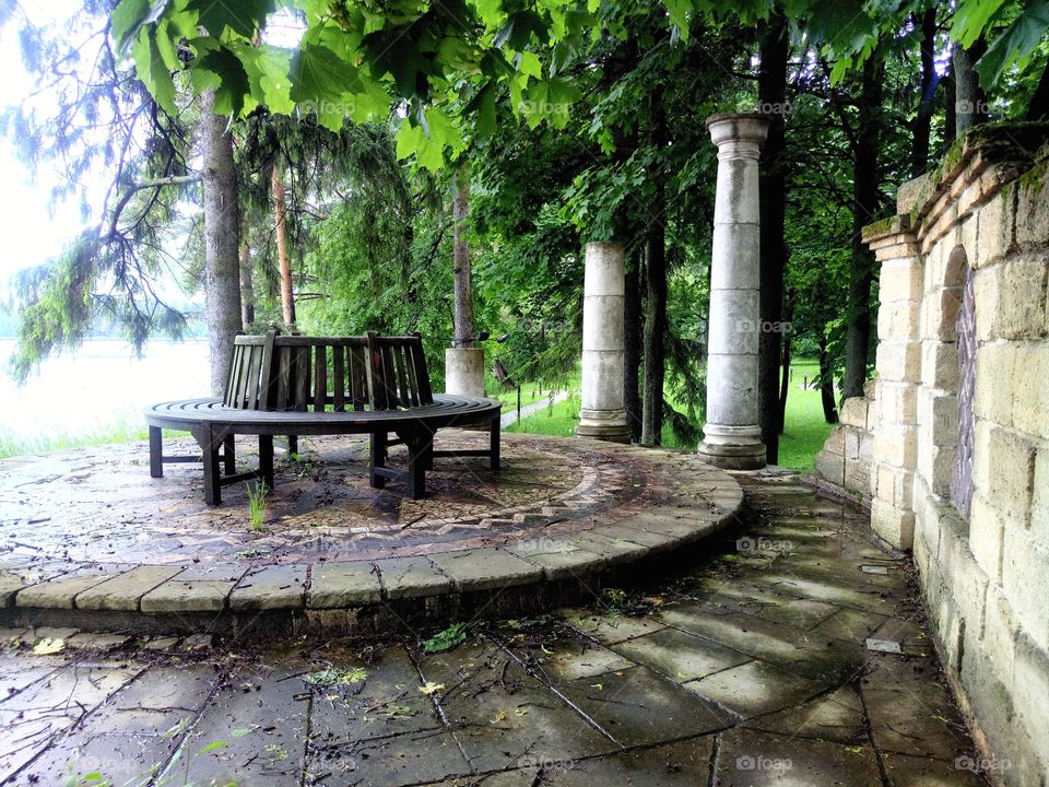 Present. Круглая деревянная скамейка на площадке с деревьями