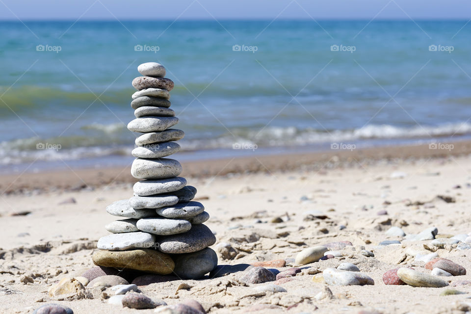stones pyramid on the beach, concept with blur sea background