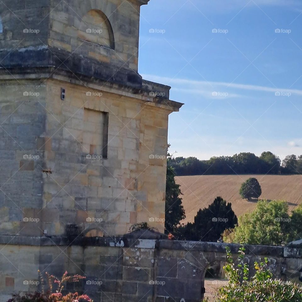 old building infront of blue sky and rolling golden english hills in background. summer day