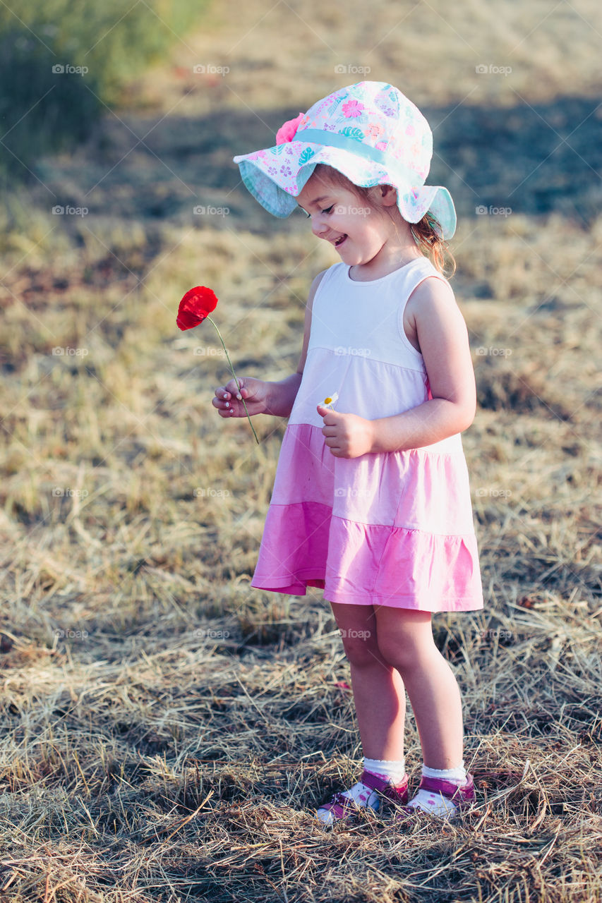 Lovely little girl in the field of wild flowers. Cute girl picking the spring flowers for her mom for Mother's Day in the meadow. Spending time close to nature