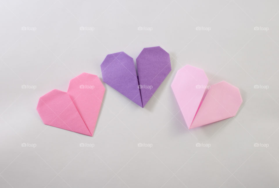 Three origami paper hearts in pink and purple. Paper craft.