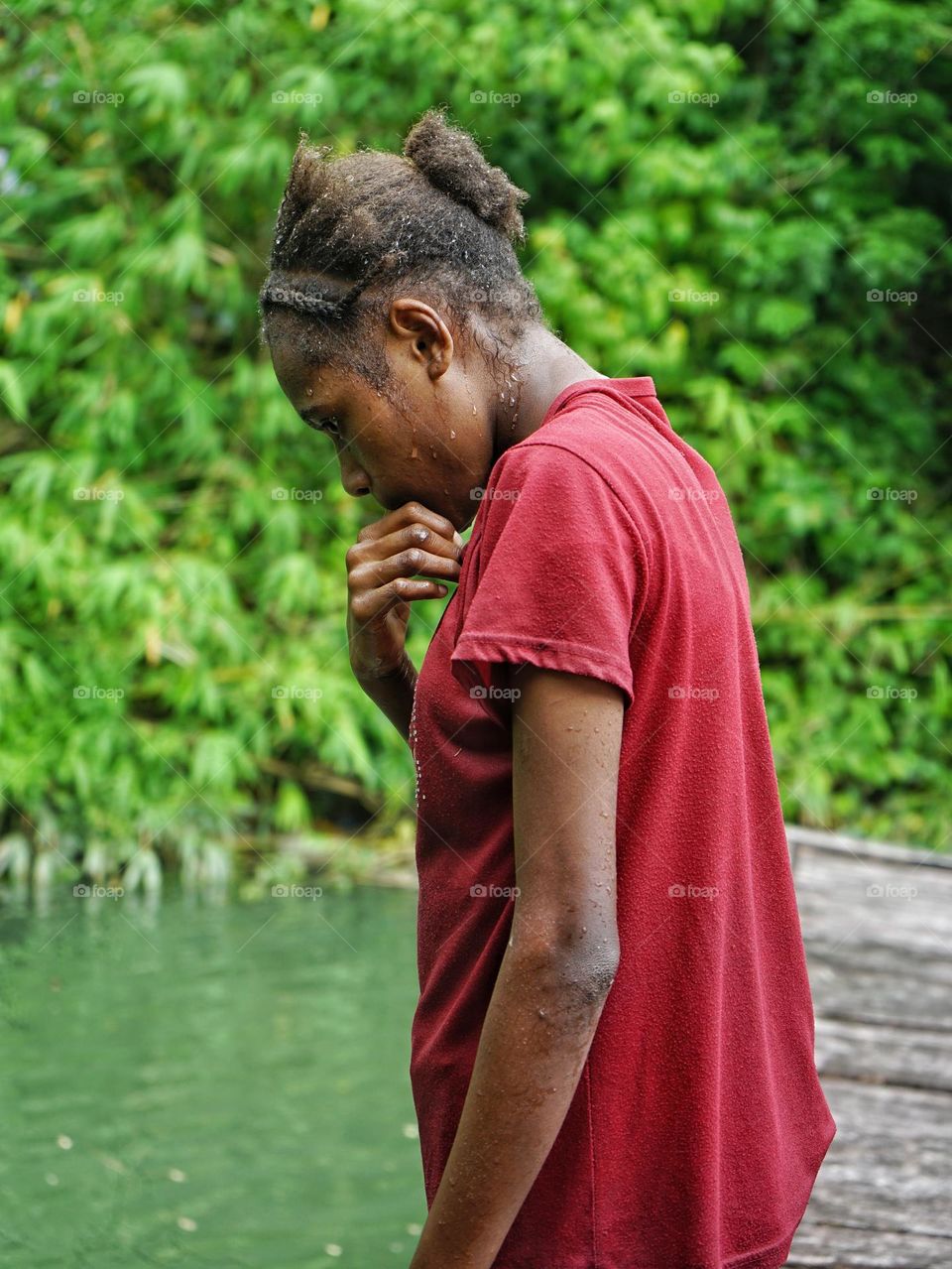 A teenage girl is resting on the edge of the pier after finishing swimming.