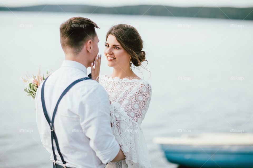 Happy newly married couple, smiling bride brunette young woman with the boho style bouquet with groom, close up portrait outdoors