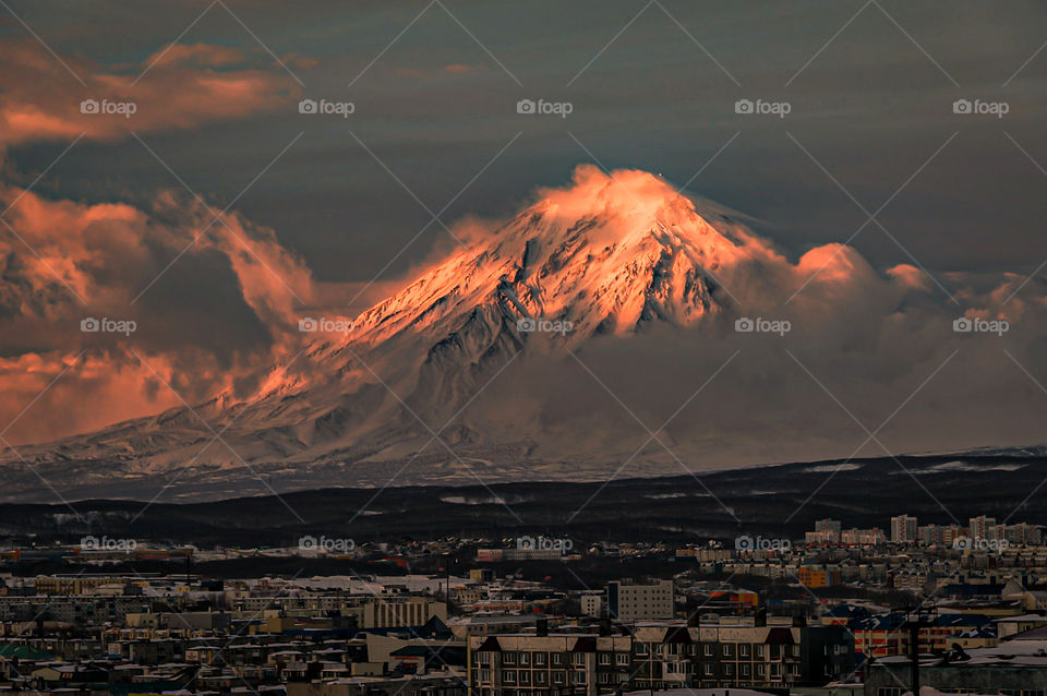 Petropavlovsk-Kamchatsky city against the backdrop of the Koryaksky volcano lit by the setting sun