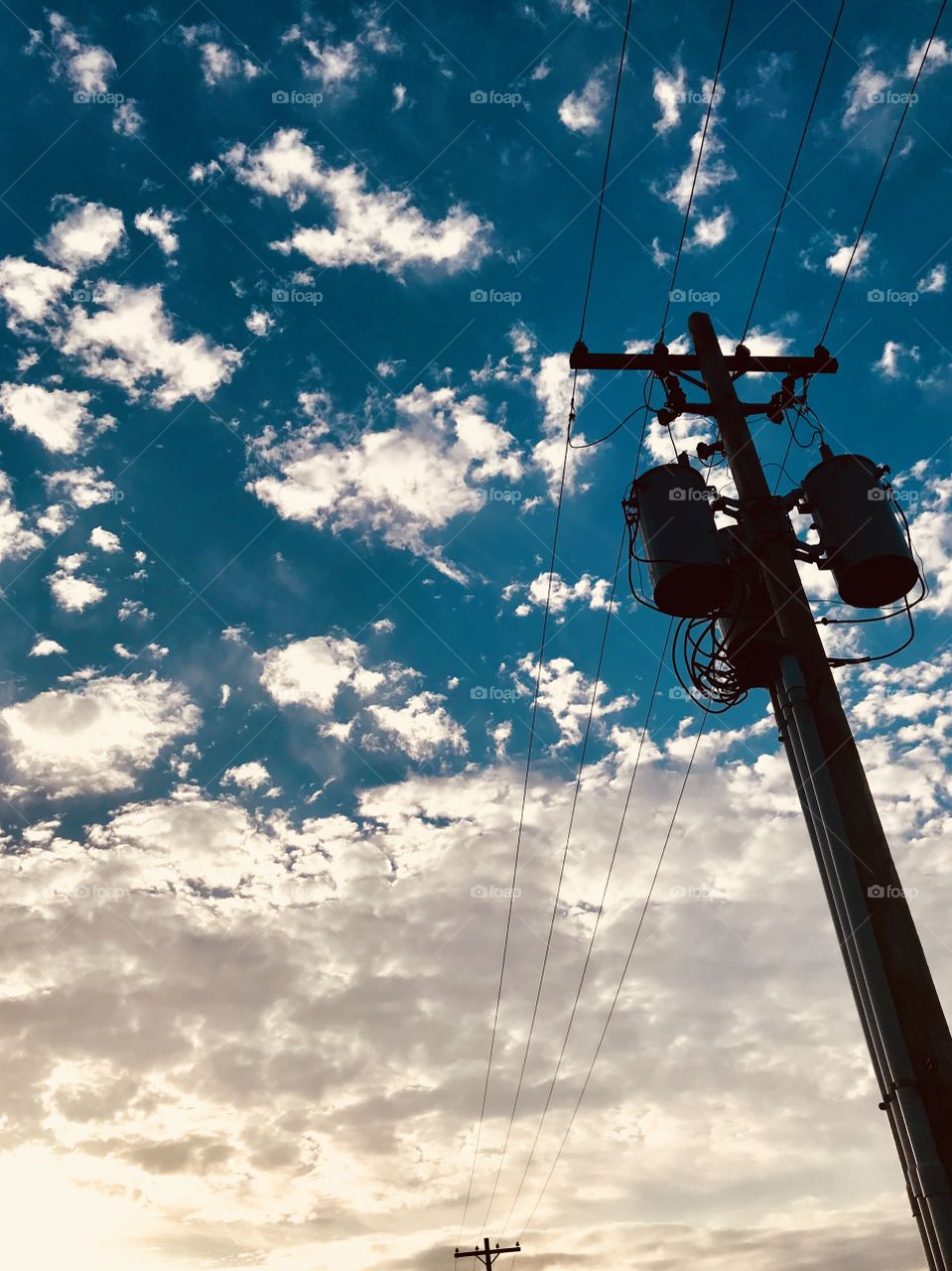 Power lines contrasted with a cloudy sky. 