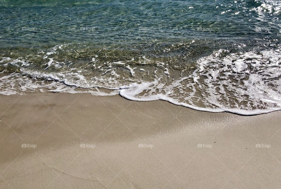Crystal clear Gulf of Mexico closeup of beach on sunny day 