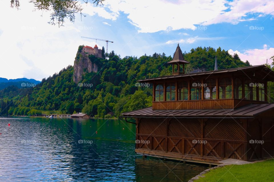 beautiful wooden hut on green side of Bled, with the castle on the hill and blue sky