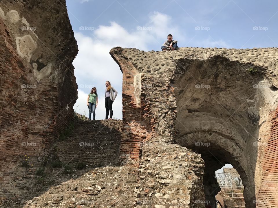 Three young people on top of an old and forgotten Italian amphitheater.