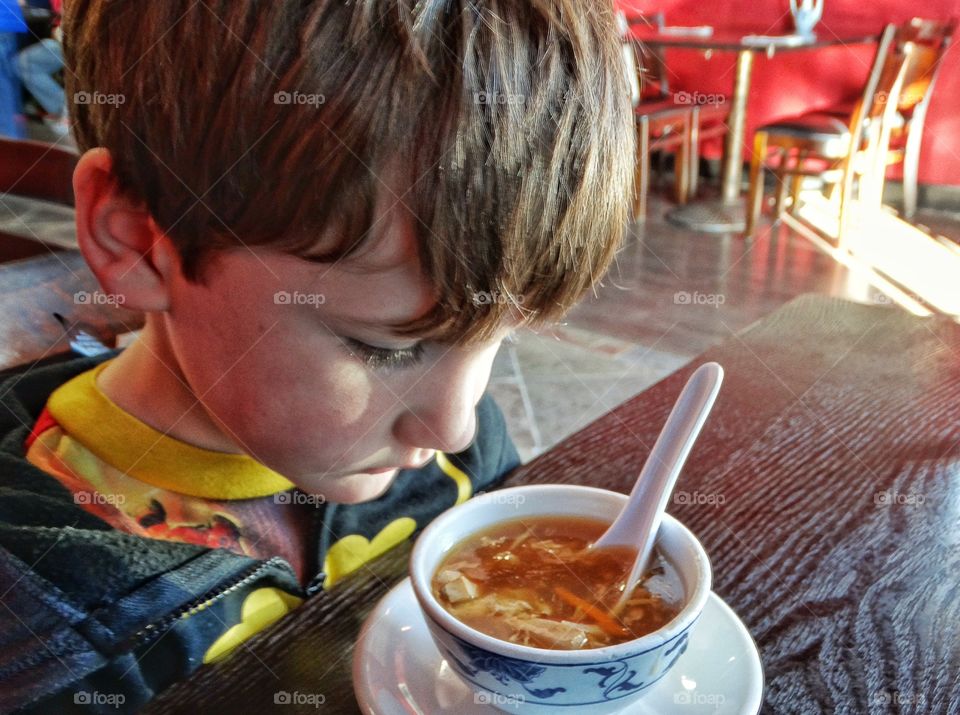 Close-up of a boy looking at soup in bowl