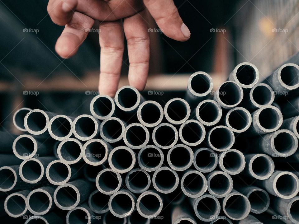 Close-uo of a cropped hand choosing a pvc pipes in a hardware shope