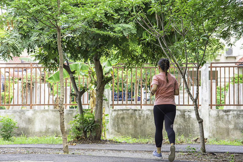 Asian women are jogging in the Park Background tree.