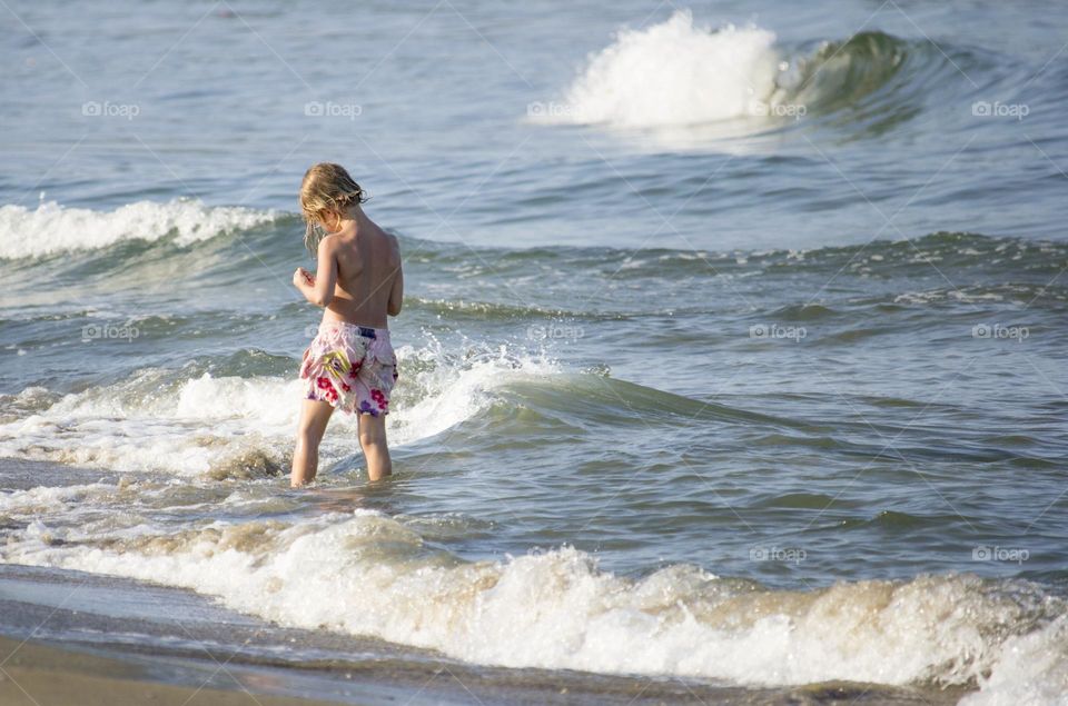 Child searching shells in the sea