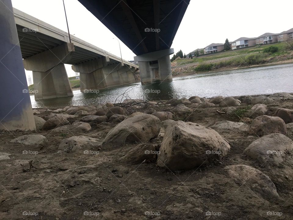Big heavy boulders sit under this concrete highway bridge going over the South Saskatchewan river, in Medicine Hat, Alberta, Canada 