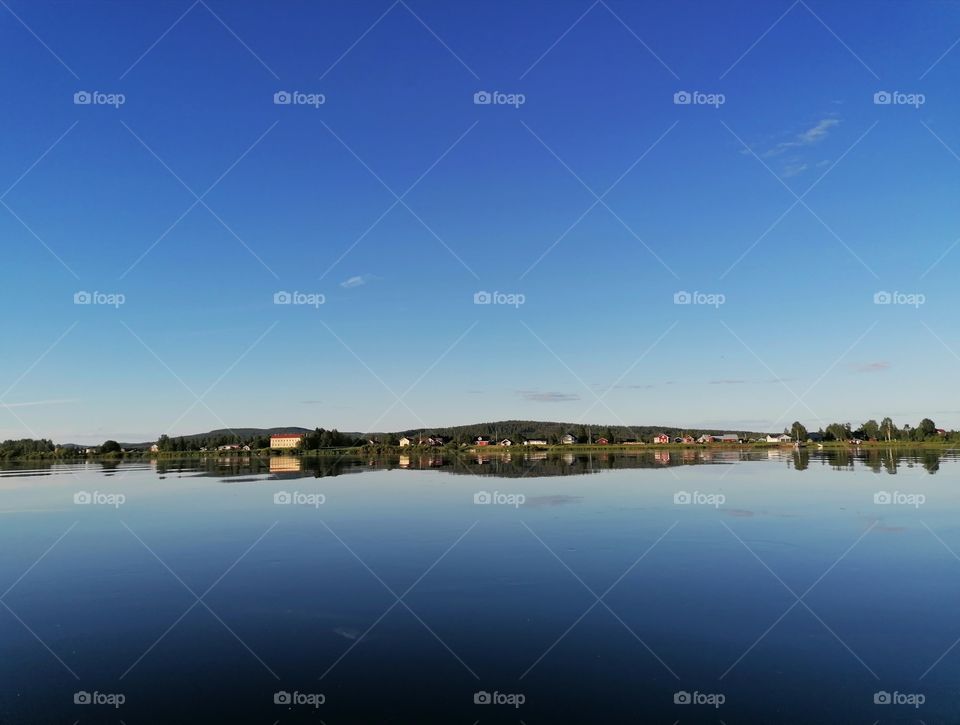 A magnificent image of a calm river with a mirror image of trees and shrubs.